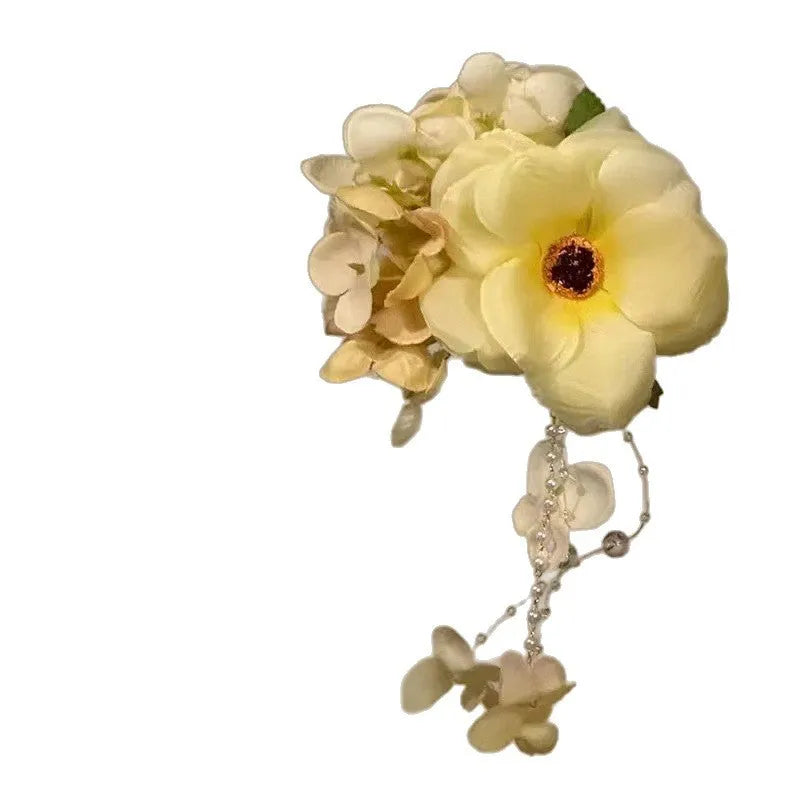 Women's floral tassel side clip hair accessory in purple or yellow on white background.