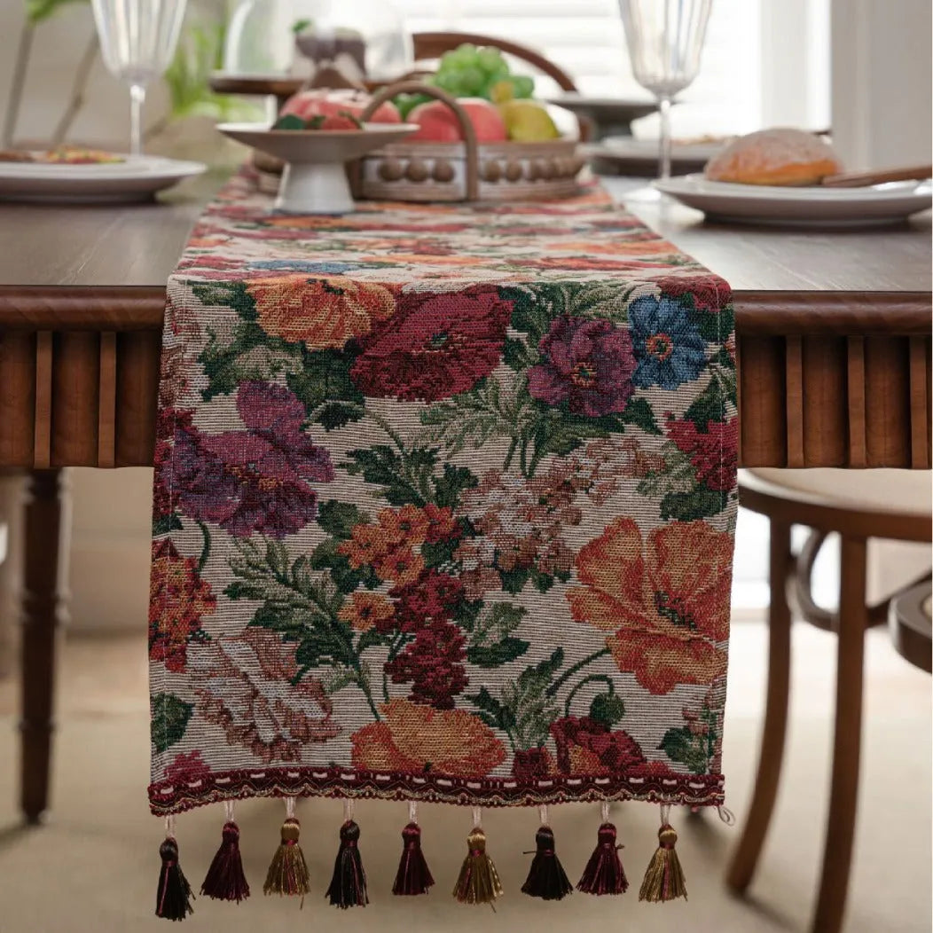 Beige polyester jacquard table runner with long tassels and a floral leaf pattern laid on a table.