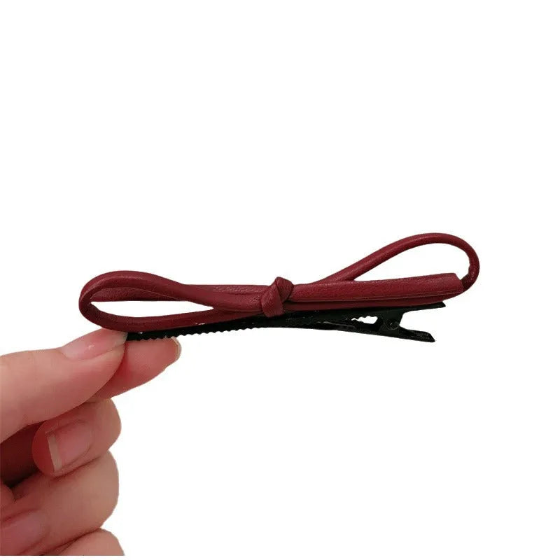Wine red leather bow-shaped barrette hair clip on a white background.