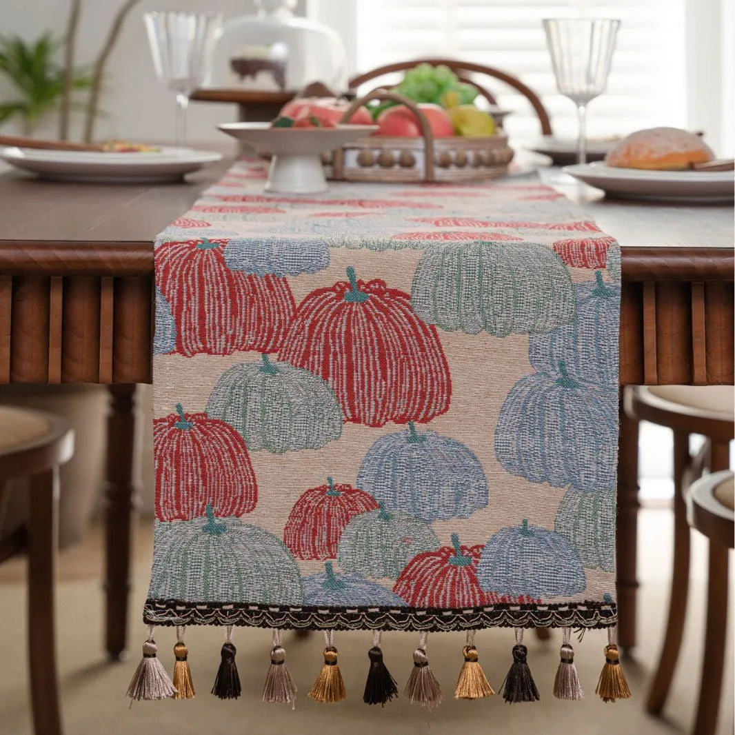 Beige polyester jacquard table runner with long tassels and a floral leaf pattern laid on a table.