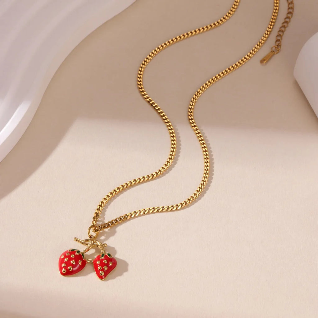 Alloy strawberry fruit pendant necklace on stainless steel chain with red charm and white gradient background.