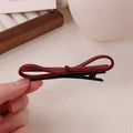 Wine red leather bow-shaped barrette hair clip on a white background.