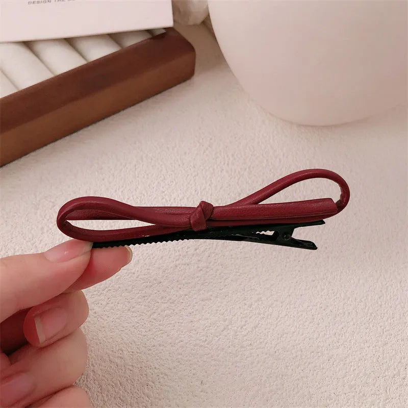 Wine red leather bow-shaped barrette hair clip on a white background.