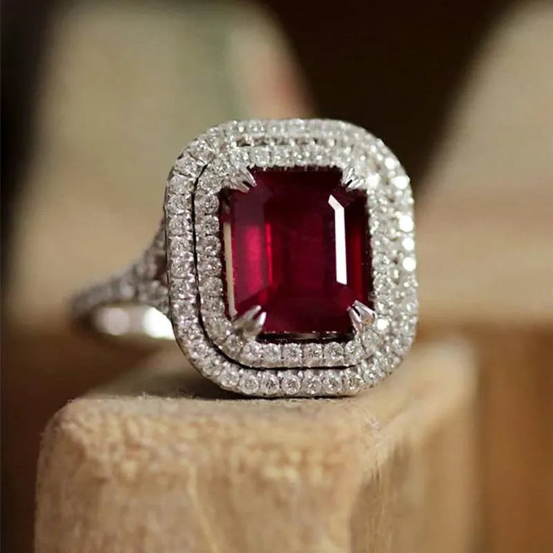 Women's copper square geometric ring with red rhinestones on a finger.