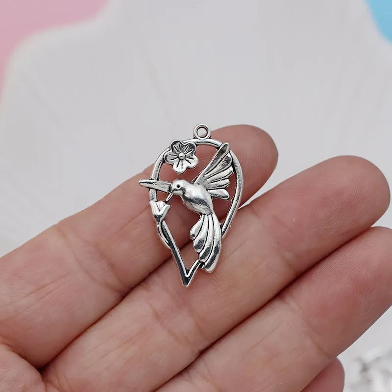 Close-up of a silver-toned alloy magpie bird pendant charm with electroplated finish, shown from the front.