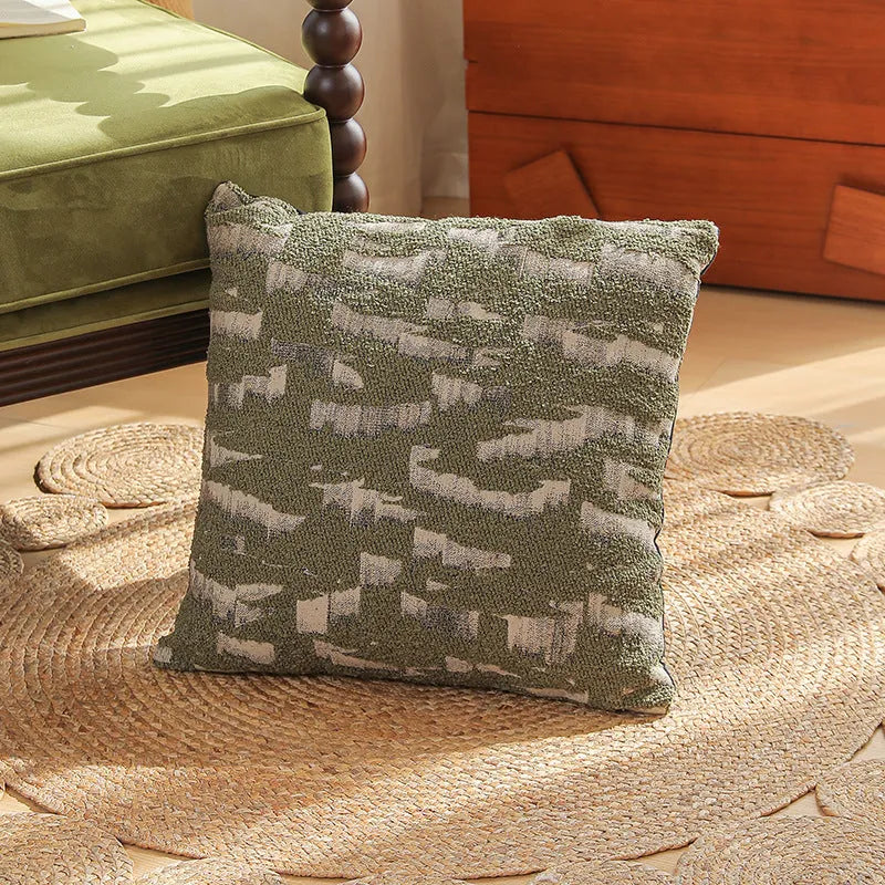 Square jacquard cushion cover with a detailed woven botanical pattern in a retro colour, shown on a grey sofa.
