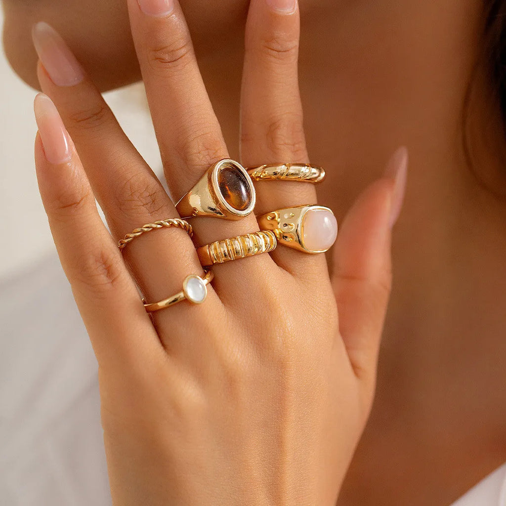 Six light gold irregular alloy rings with geometric shapes on a light background