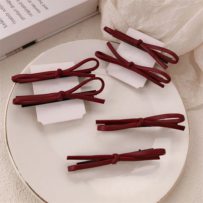 Wine red leather bow-shaped barrette hair clip on a white background.