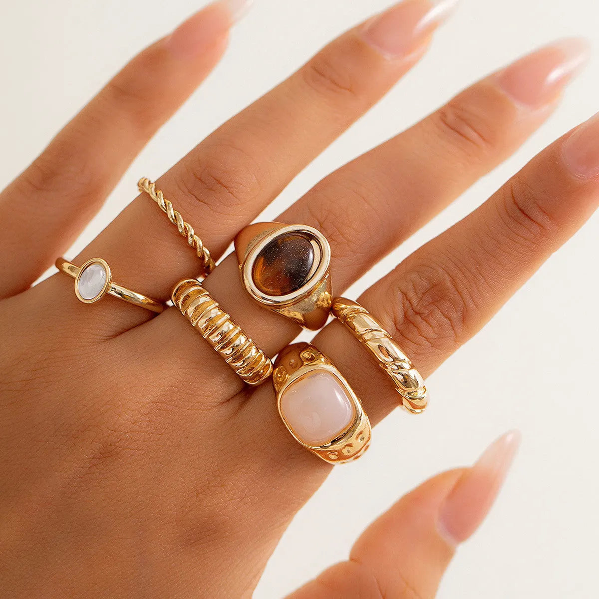 Six light gold irregular alloy rings with geometric shapes on a light background