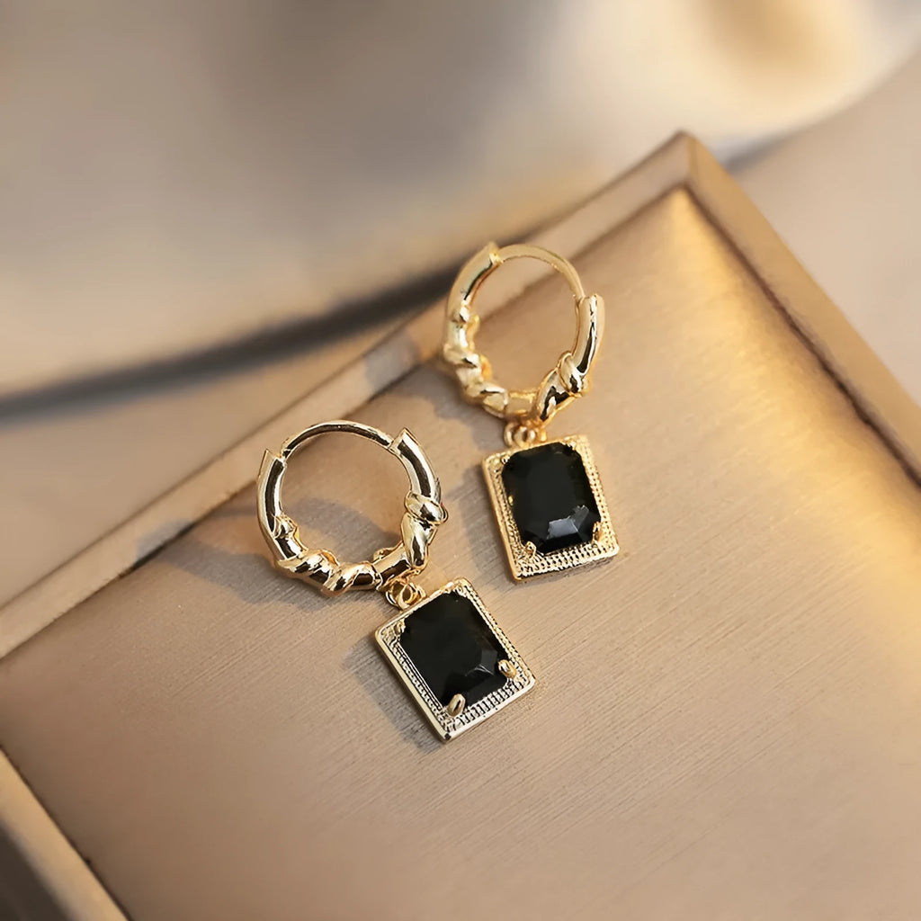 A pair of square geometric copper earrings with a black zircon in a French court retro setting.