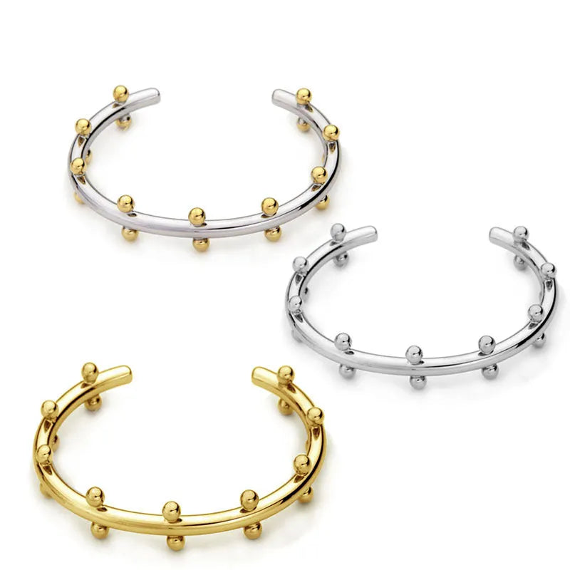 Stainless steel C-shaped bracelet with textured rivet and bean bead design in gold colour.
