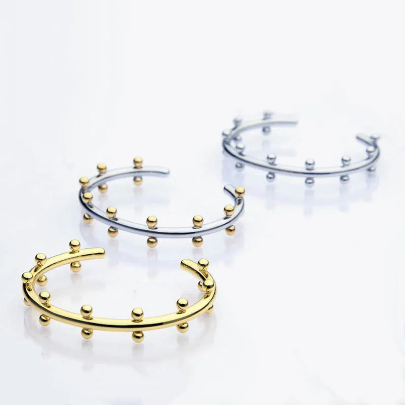 Stainless steel C-shaped bracelet with textured rivet and bean bead design in gold colour.