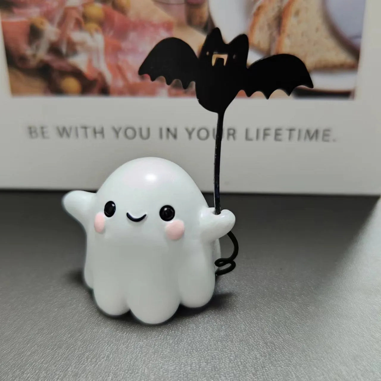 Small resin statue of a ghost walking a dog, a Halloween decoration.