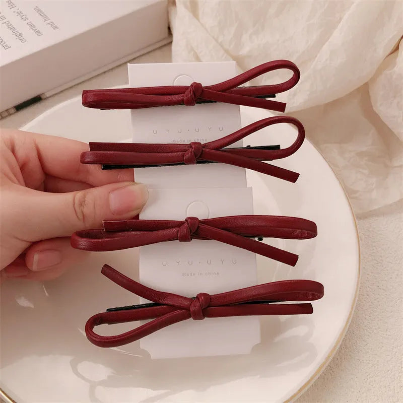 Wine red leather bow-shaped barrette hair clip on a white background.