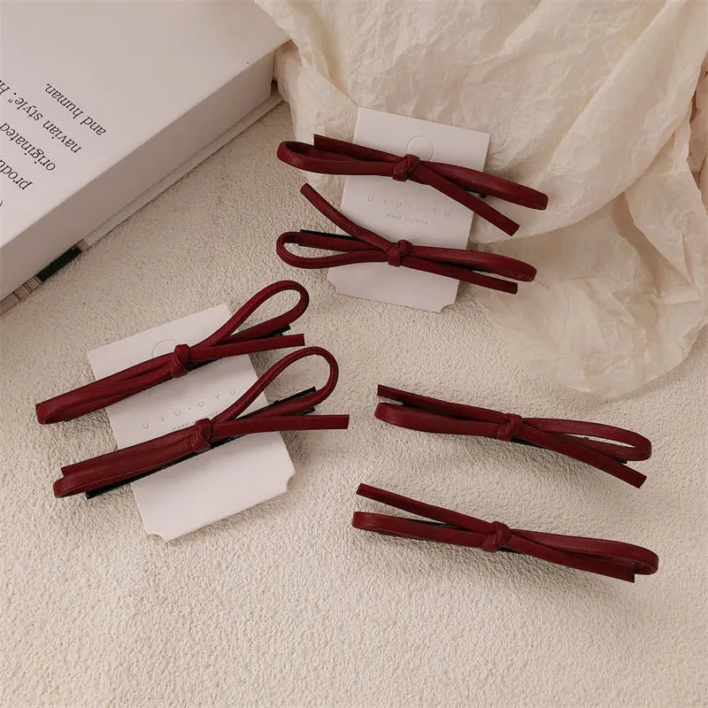 Wine red leather bow-shaped barrette hair clip on a white background.