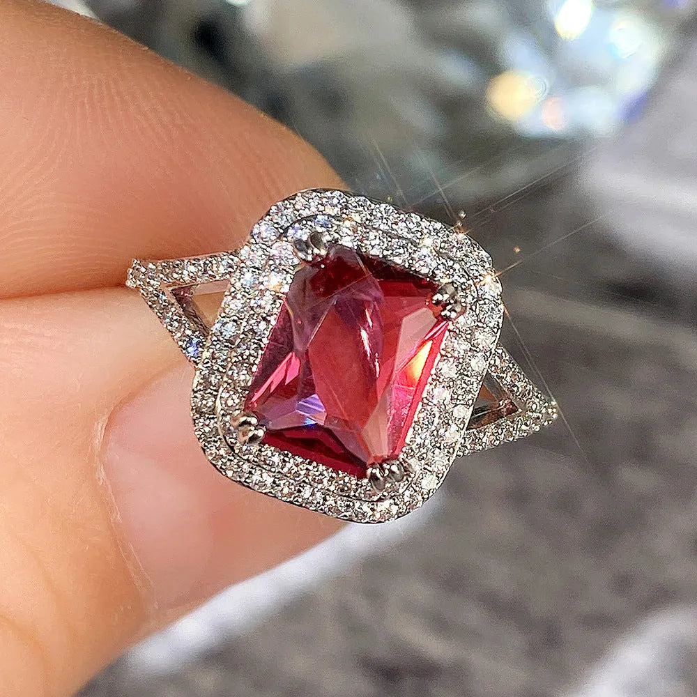 Women's copper square geometric ring with red rhinestones on a finger.