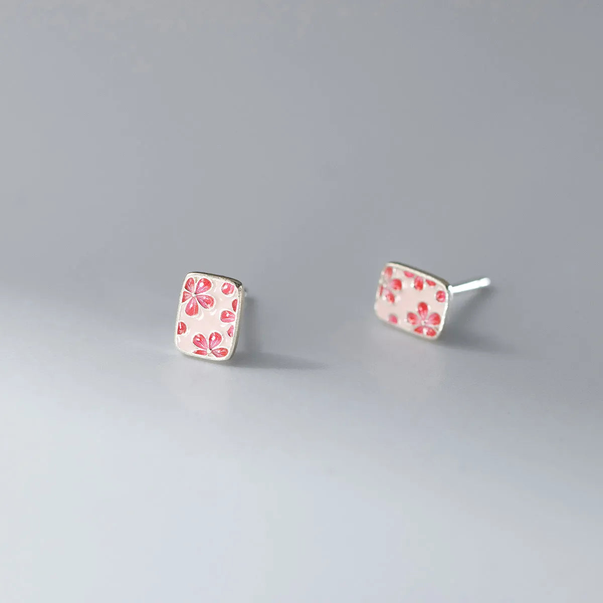 S925 sterling silver cherry blossom square stud earrings on a white background, showing polished silver finish and floral geometric design.