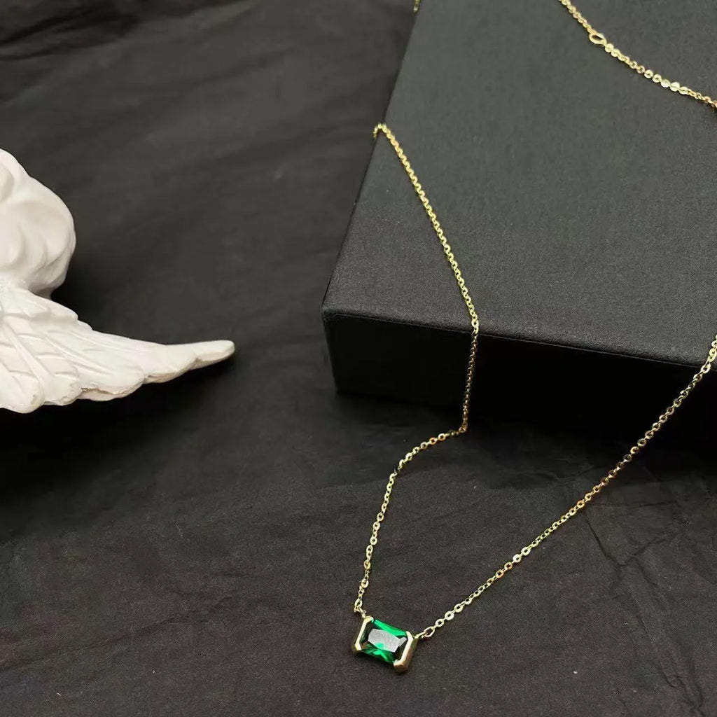 Gold geometric quadrilateral pendant necklace with inlaid cubic zirconia stones on a chain.