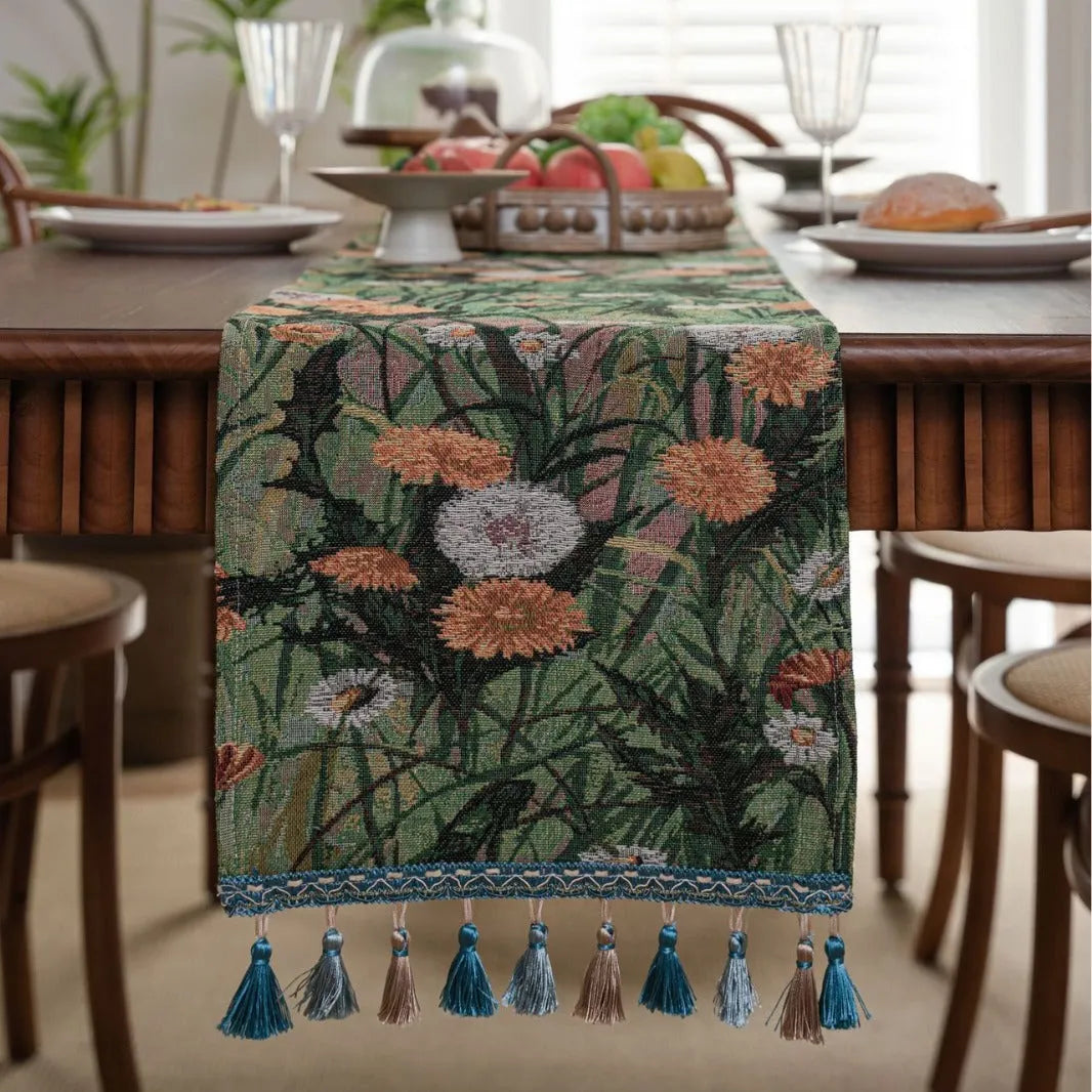 Beige polyester jacquard table runner with long tassels and a floral leaf pattern laid on a table.
