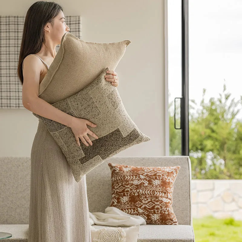 A 45cm square solid-colour cushion with stitched edges on a grey sofa.
