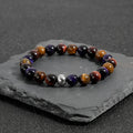Handmade elastic tiger-eye stone bracelet in geometric shapes on a wrist.