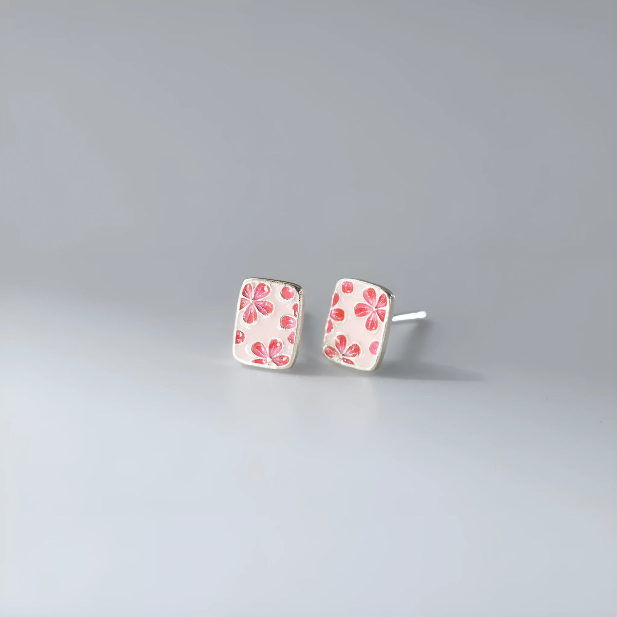 S925 sterling silver cherry blossom square stud earrings on a white background, showing polished silver finish and floral geometric design.