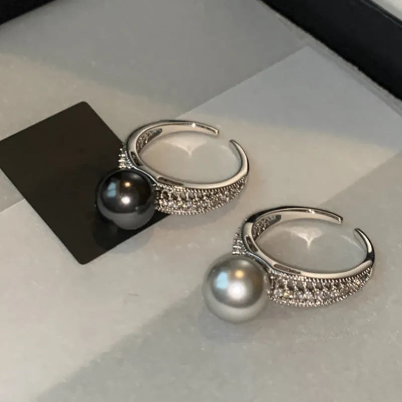 Adjustable open copper ring with geometric shape and black pearl detail on index finger
