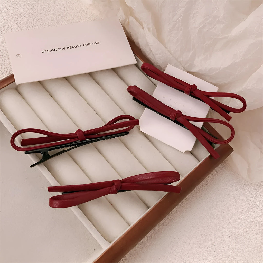 Wine red leather bow-shaped barrette hair clip on a white background.