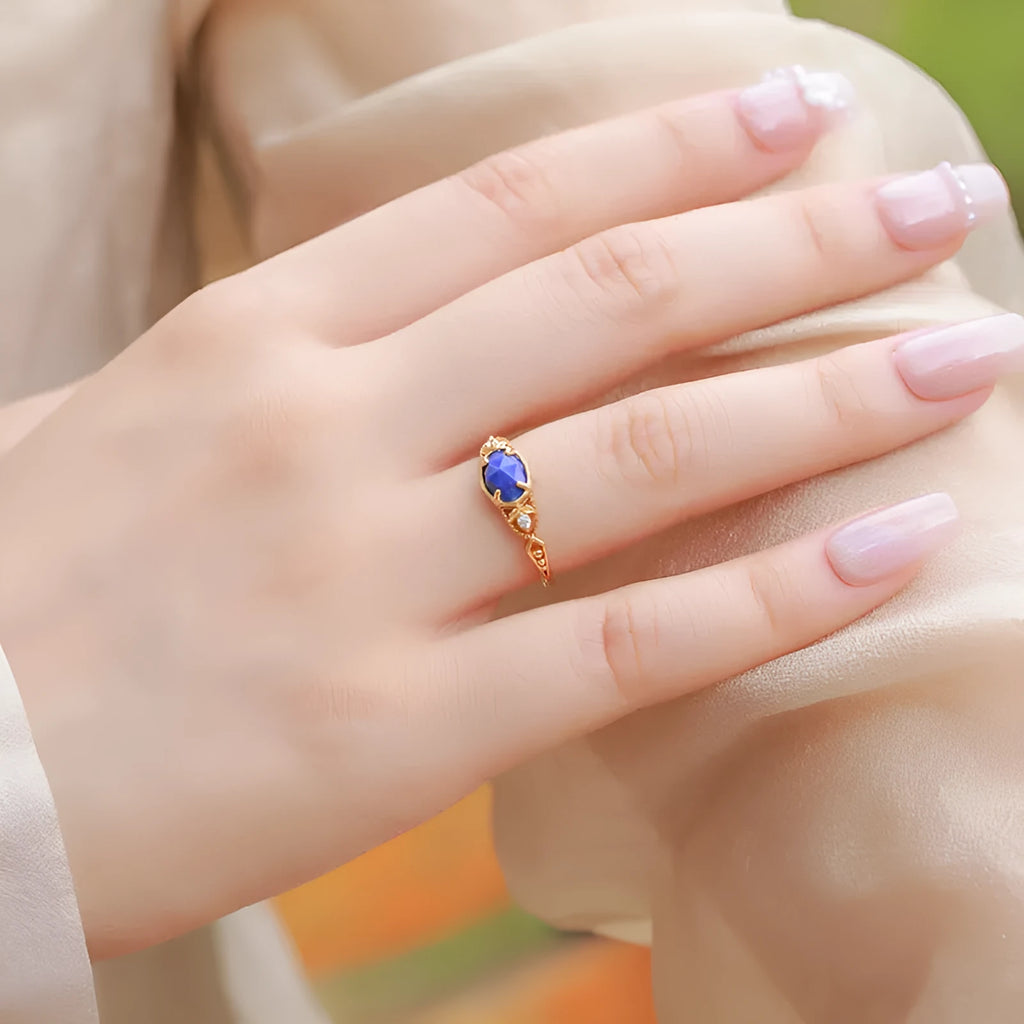 Silver geometric elliptical ring with a blue lapis lazuli stone and round decorative element.