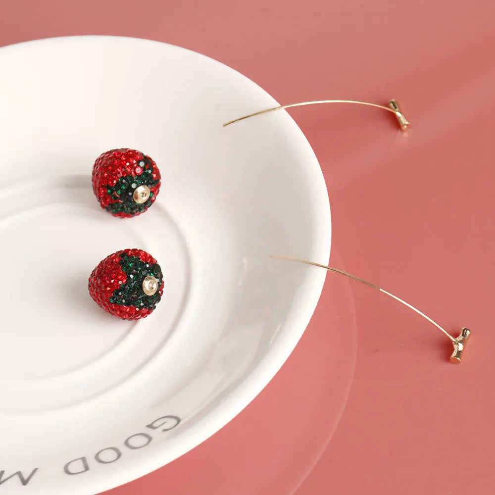 Geometric zinc alloy women's earrings with a red strawberry charm on a white background.