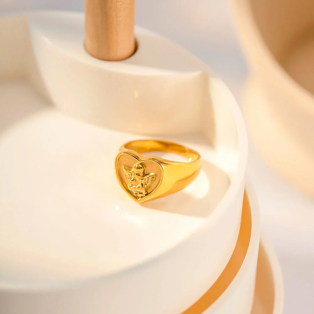 Closeup of a gold plated stainless steel ring with a heart and angel design, a classic and elegant accessory