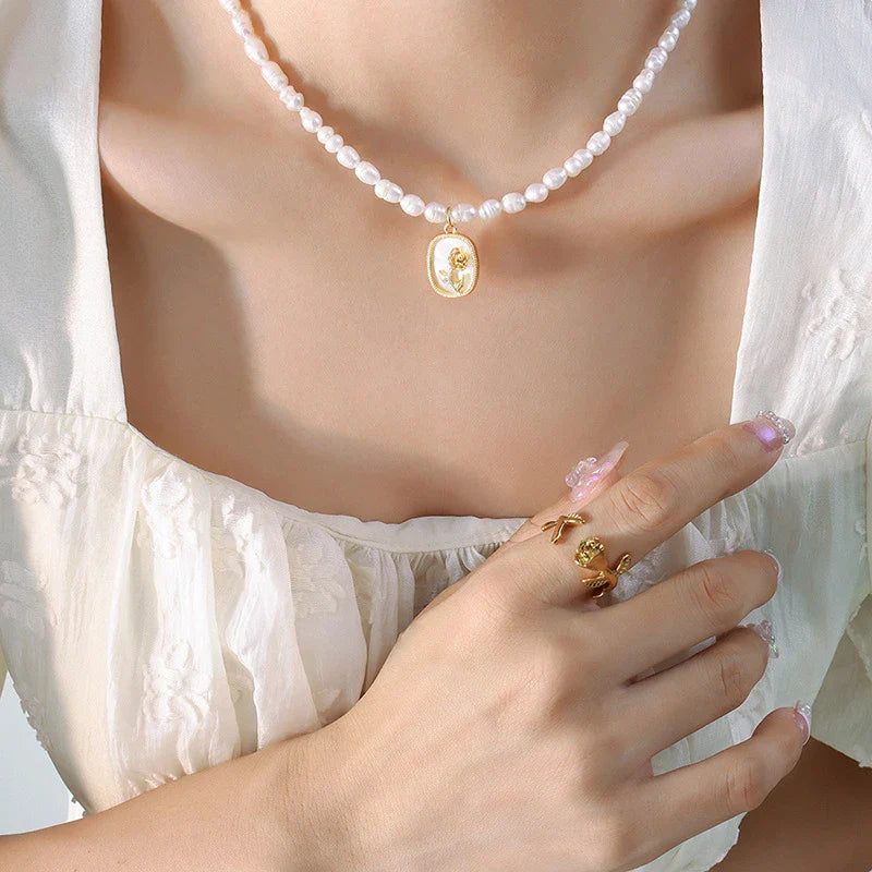 Exquisite gold-toned necklace featuring a delicate chain with embossed floral design and natural freshwater pearls accented by zirconia stones