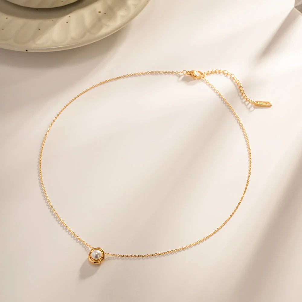 Elegant stainless steel necklace with a unique, irregular pearl pendant in a gold color, featuring a contemporary geometric design