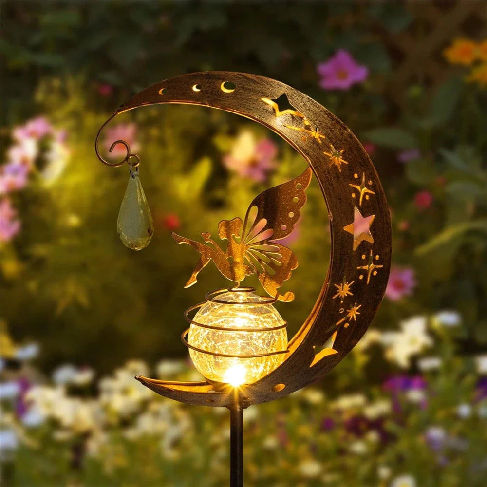 Decorative solar-powered fairy garden light with a glass globe and moon and fairy design for outdoor illumination