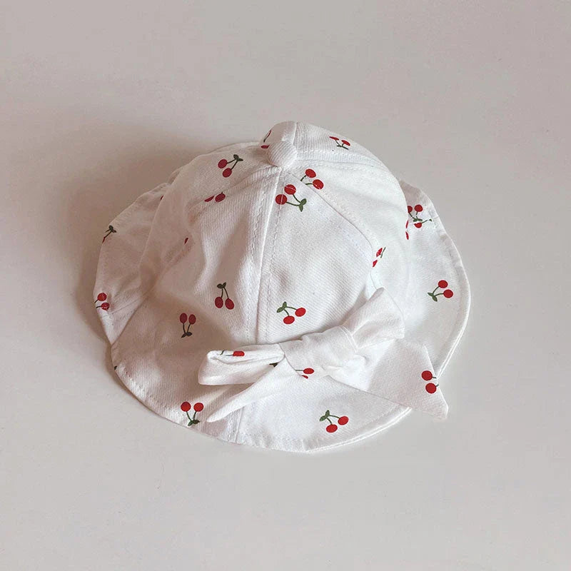 A charming bucket hat for kids featuring a delightful fruit print and cute bow detail, providing excellent sun protection and comfort.