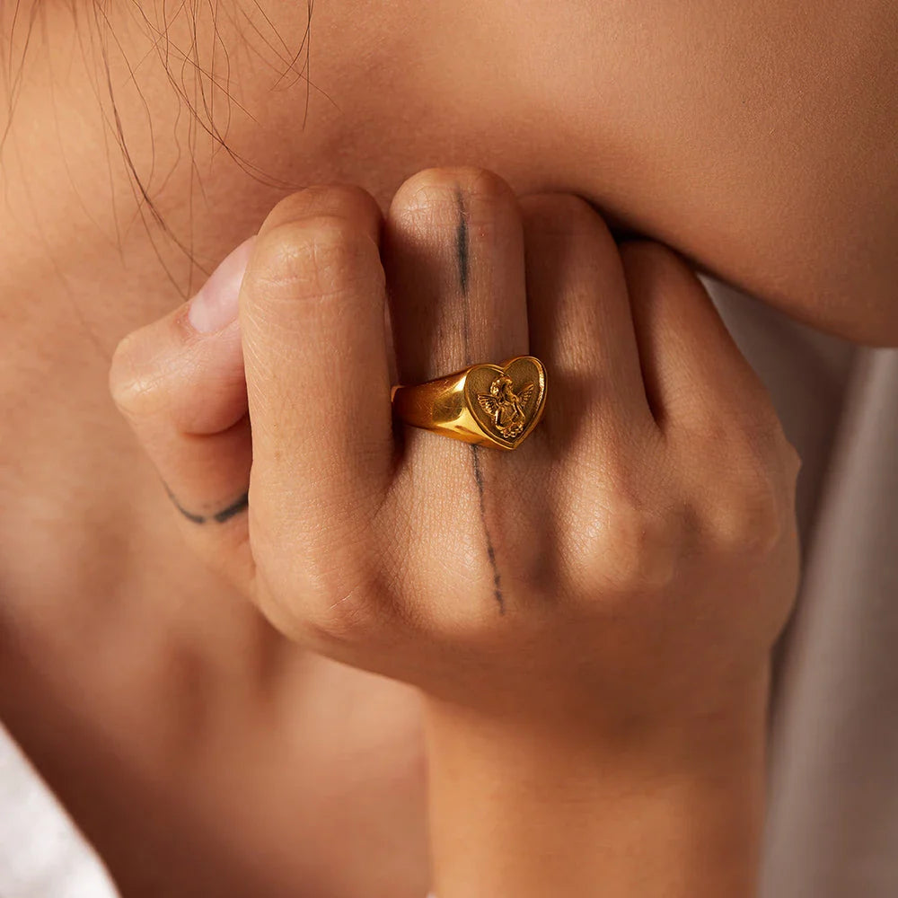 Closeup of a gold plated stainless steel ring with a heart and angel design, a classic and elegant accessory