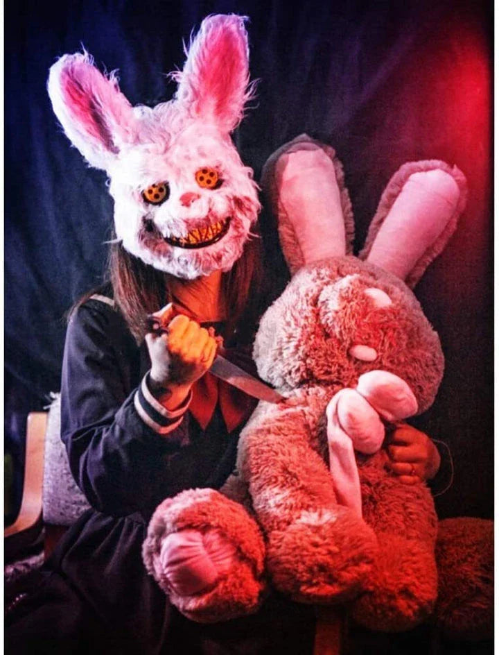 A creepy and realistic plush bunny mask with long pink ears, a bloody mouth, and glowing green eyes - perfect for Halloween and costume parties.