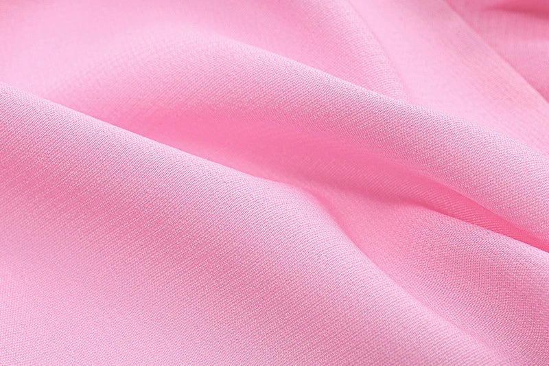 A pink ruffled crop top with a heart-shaped bow accent, made from stretch chiffon fabric for the modern Kiwi girl's style.