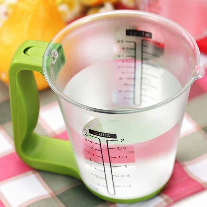 A green digital measuring cup with an LCD display integrated into the handle, designed in New Zealand for precise kitchen measurements