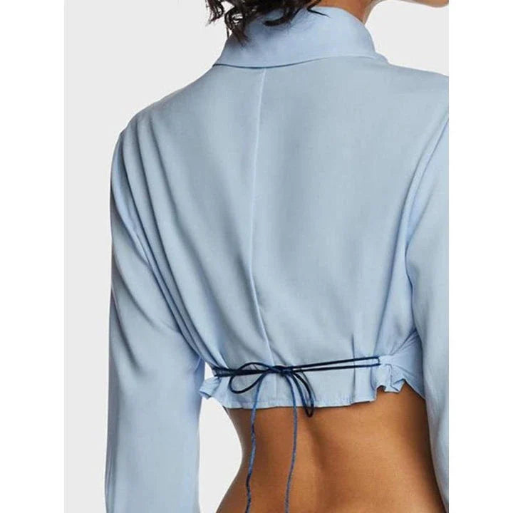 Stylish blue blouse with lace-up back and V-shaped hem, a versatile wardrobe staple with a touch of modern elegance.