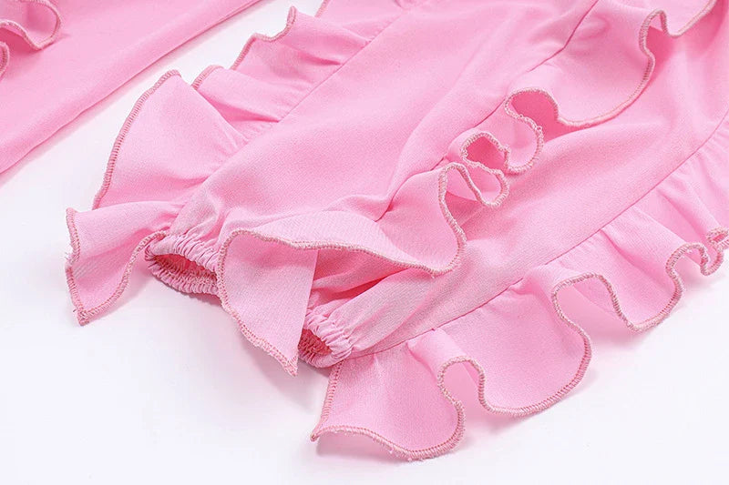 A pink ruffled crop top with a heart-shaped bow accent, made from stretch chiffon fabric for the modern Kiwi girl's style.