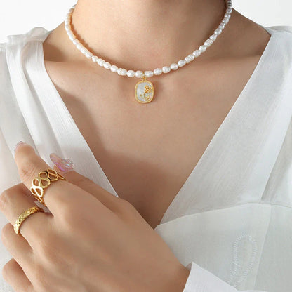 Exquisite gold-toned necklace featuring a delicate chain with embossed floral design and natural freshwater pearls accented by zirconia stones