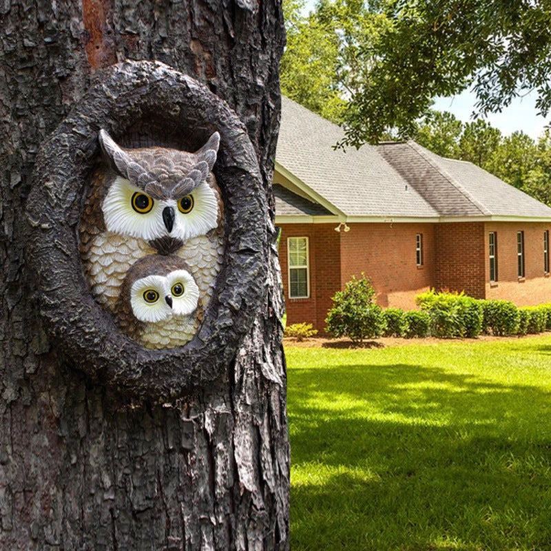 Charming resin mother and child owl ornament hanging from a tree branch in a Kiwi garden