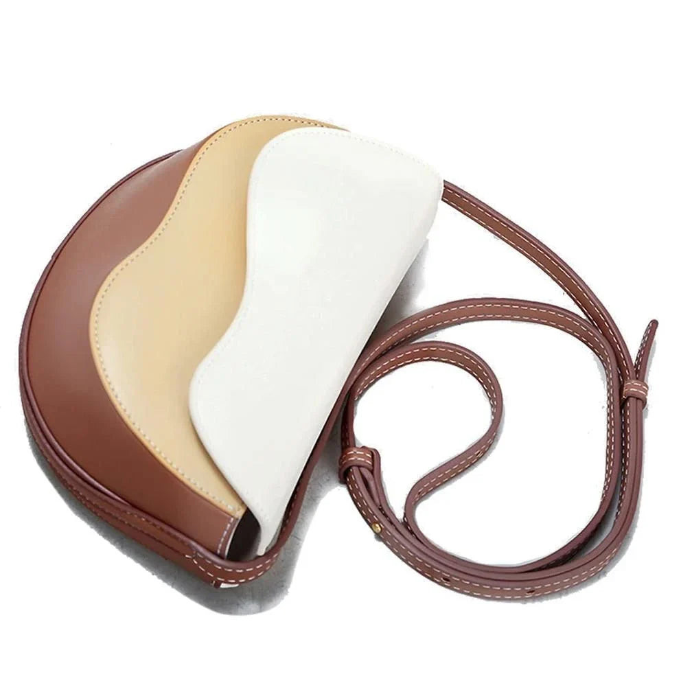 Stylish contrast color crossbody saddle bag with patchwork design, flap closure, and adjustable strap