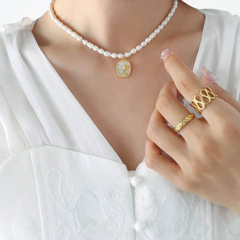 Exquisite gold-toned necklace featuring a delicate chain with embossed floral design and natural freshwater pearls accented by zirconia stones