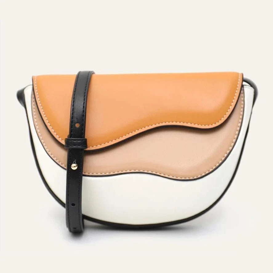 Stylish contrast color crossbody saddle bag with patchwork design, flap closure, and adjustable strap