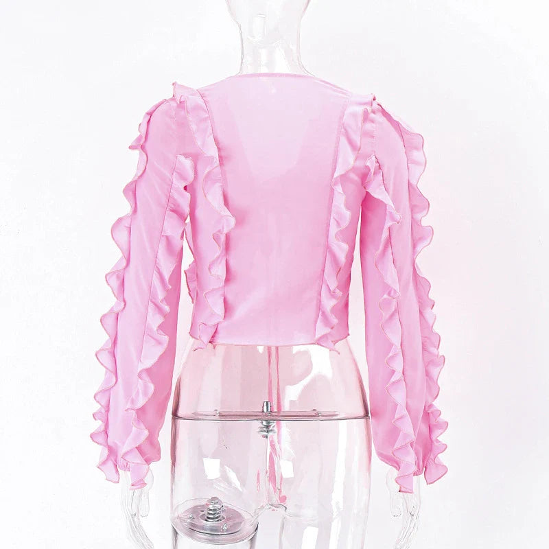 A pink ruffled crop top with a heart-shaped bow accent, made from stretch chiffon fabric for the modern Kiwi girl's style.