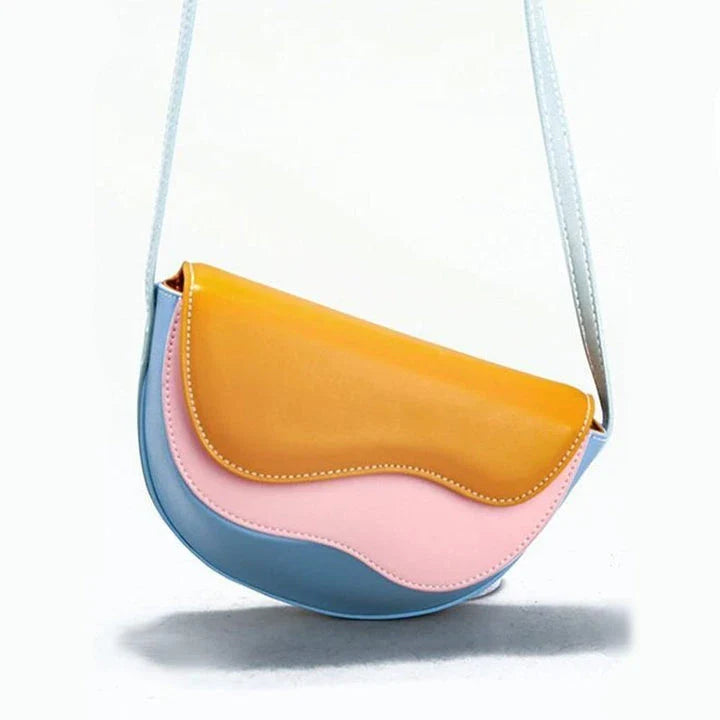 Stylish contrast color crossbody saddle bag with patchwork design, flap closure, and adjustable strap