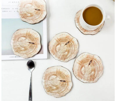 Set of 6 natural timber coasters in various grain patterns, protecting a mug on a wooden surface