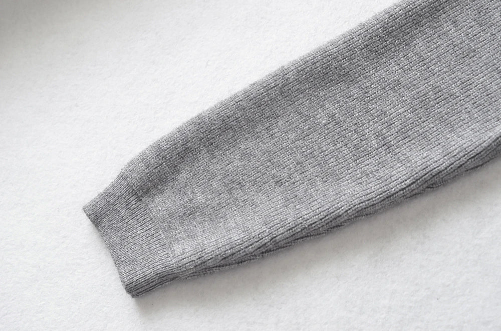 Stylish knitwear vest in a classic black or neutral colour, featuring a V-neck collar and long sleeves for a polished, versatile look.